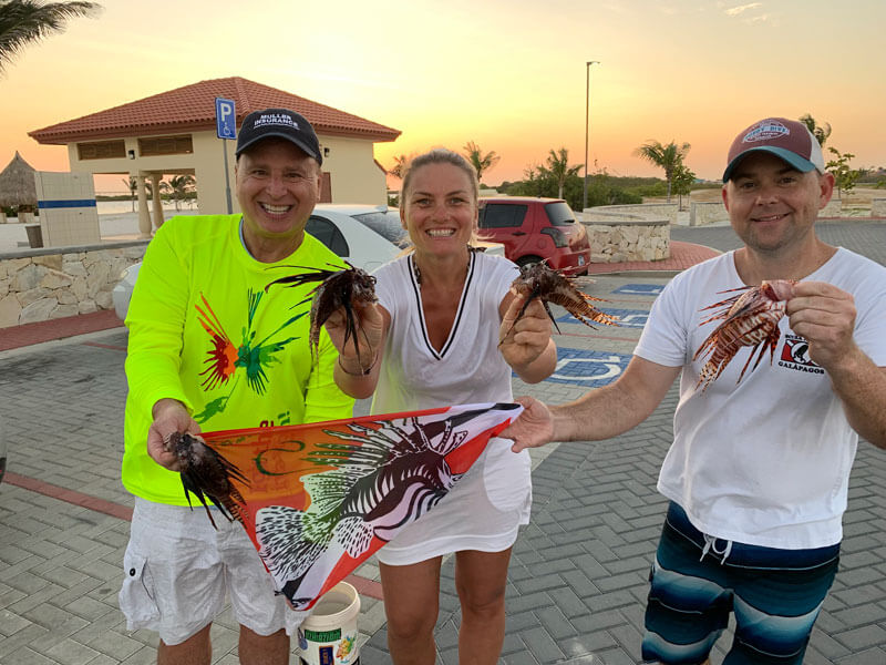 Lionfish hunters Roger J. Muller, Jr. and Jared Casperson hold up their catch with Roger’s wife, Andrea Muller