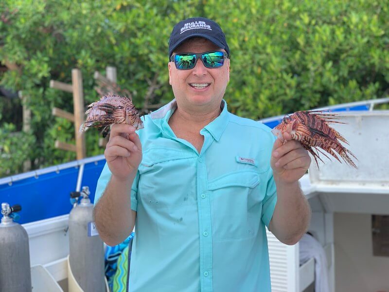 Roger J. Muller, Jr. holding 2 lionfish