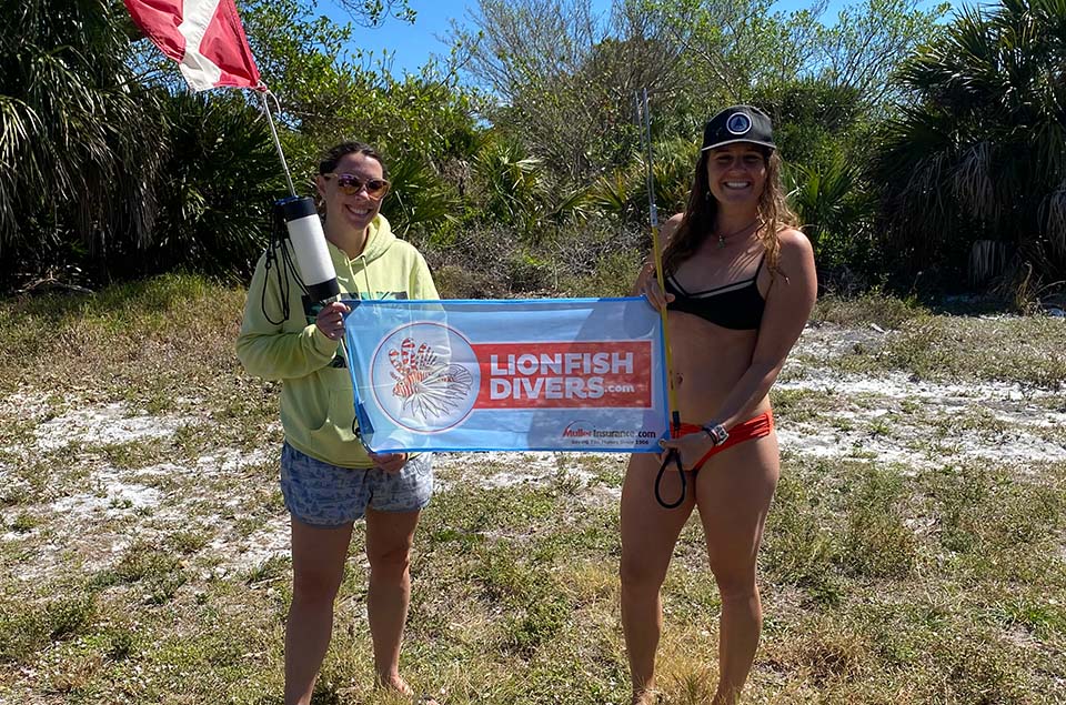 Christine Raininger and friend holding lionfishdivers.com flag