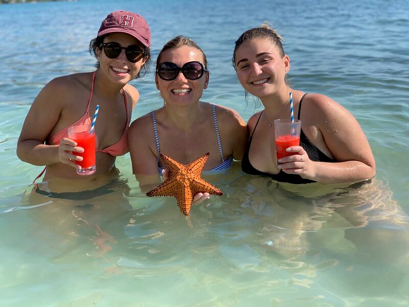 Threee girls holding starfish in the ocean