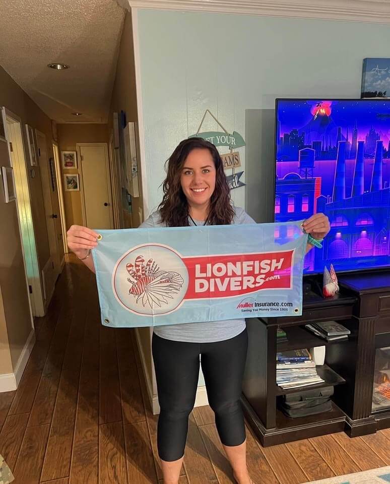 Sara Newton holding lionfishdivers.com flag