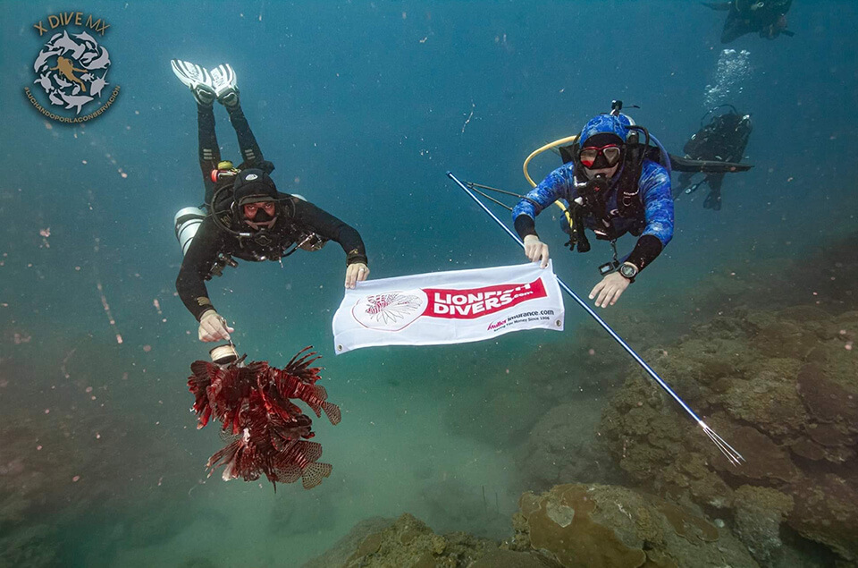 Armando Abreu from X DIVE MX holding lionfishdivers.com flag underwater