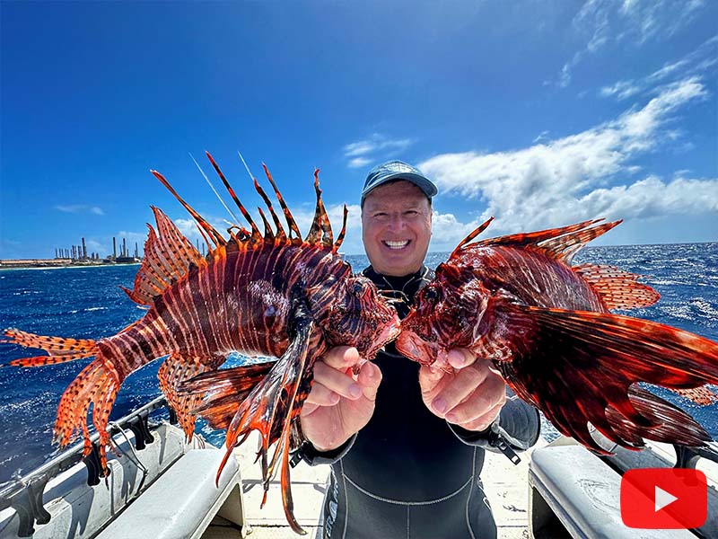 Roger J. Muller, Jr. holding 2 huge lionfish in Aruba