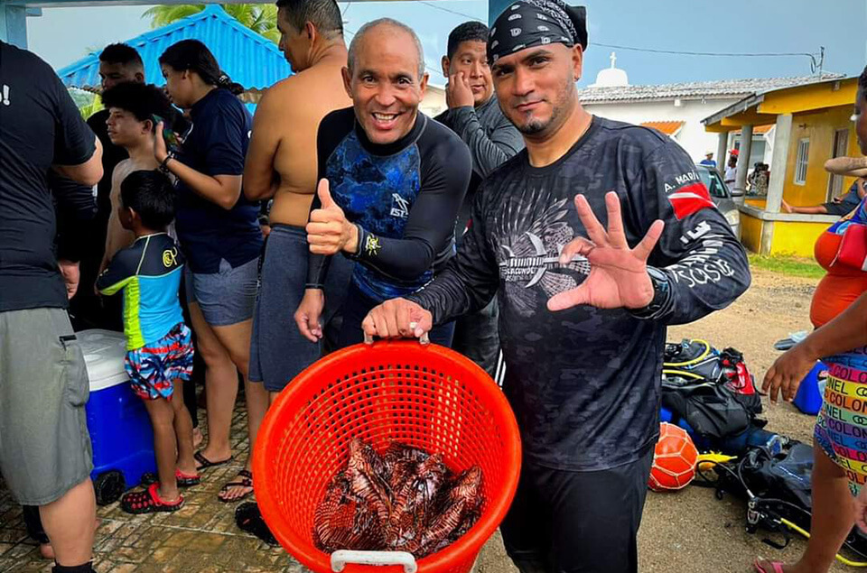 Alfredo Marin holding bucket of lionfish