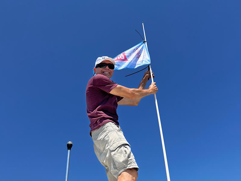 Man putting lionfishdivers.com flag on boat flag pole