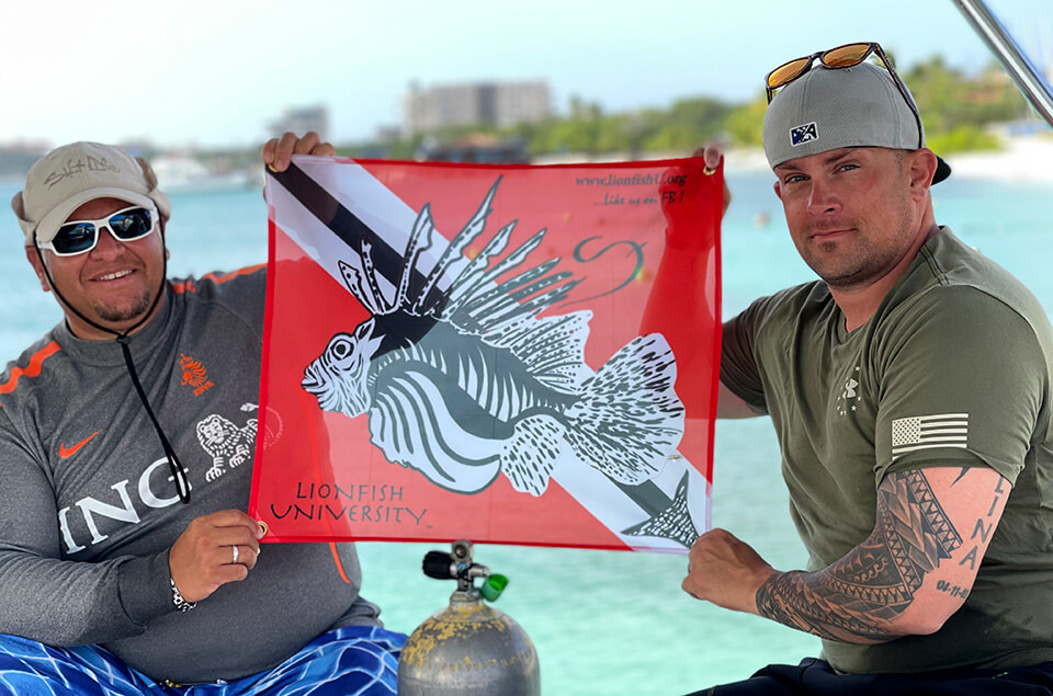 Justin Williams in Aruba holding Lionfish University flag
