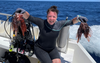 Marie-Anne Claveau holding 2 lionfish on a dive boat