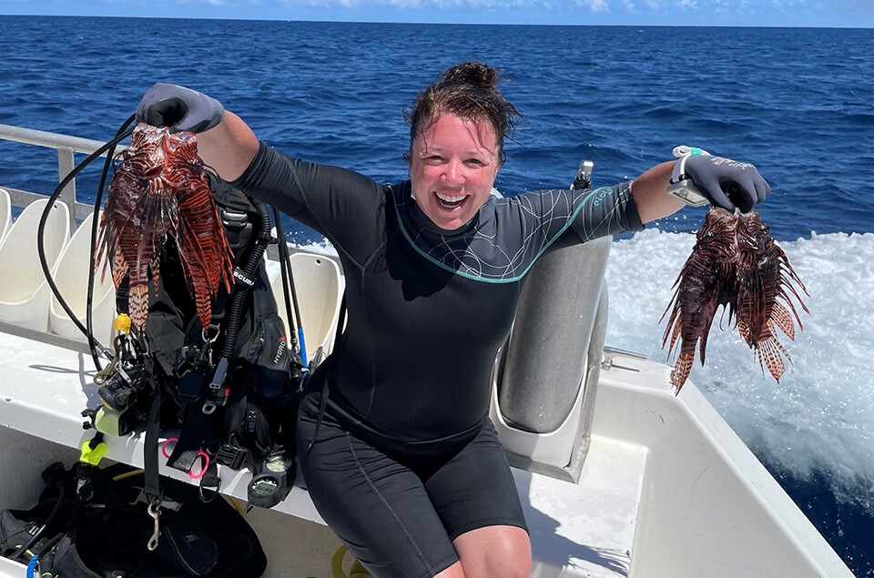 Marie-Anne Claveau holding 2 lionfish on a dive boat
