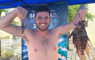 Andres Felipe Valencia holding two lionfish, one very small and one very large