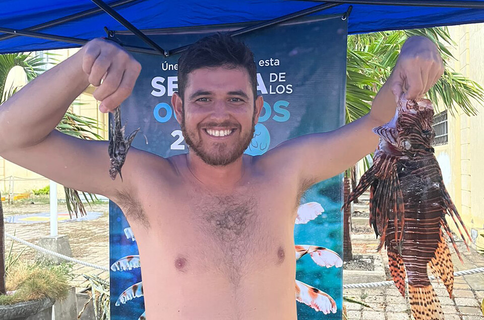 Andres Felipe Valencia holding two lionfish, one very small and one very large