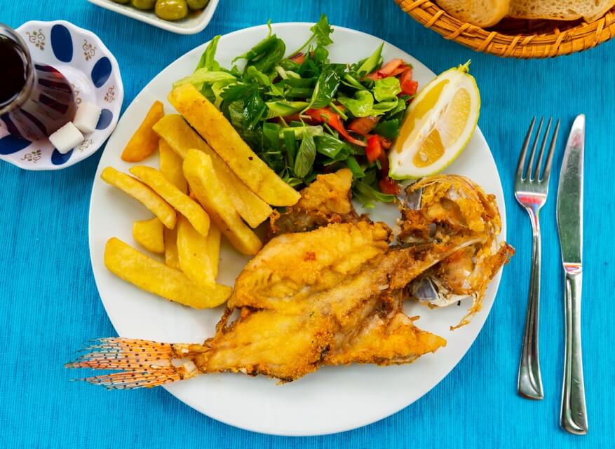 Fried lionfish with fries and salad served at a tropical restaurant