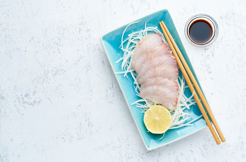 Raw lionfish sashimi on a plate with chopsticks